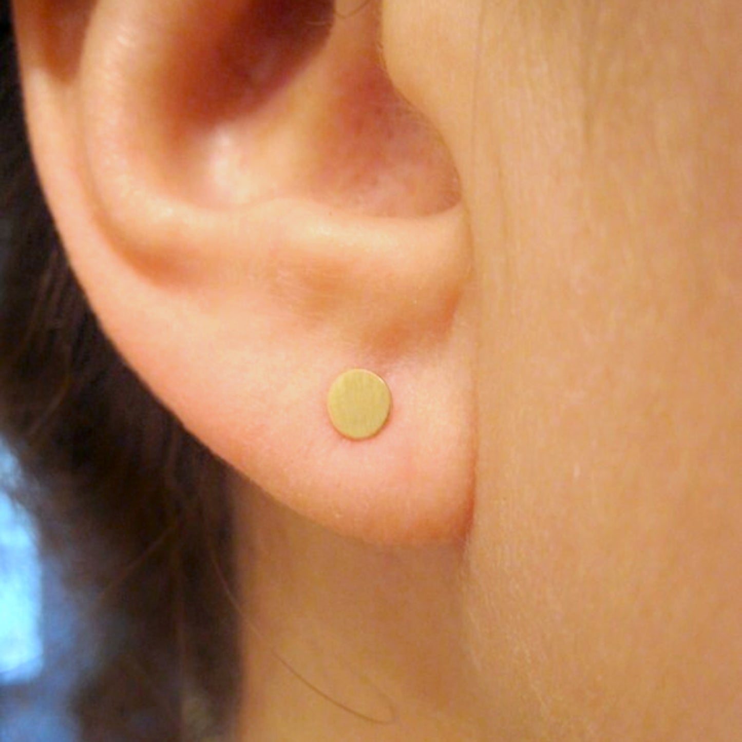 Woman wearing 4mm gold circle stud earrings for scale