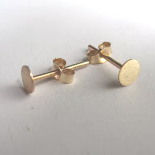 Close-up of polished gold circle studs on a white background