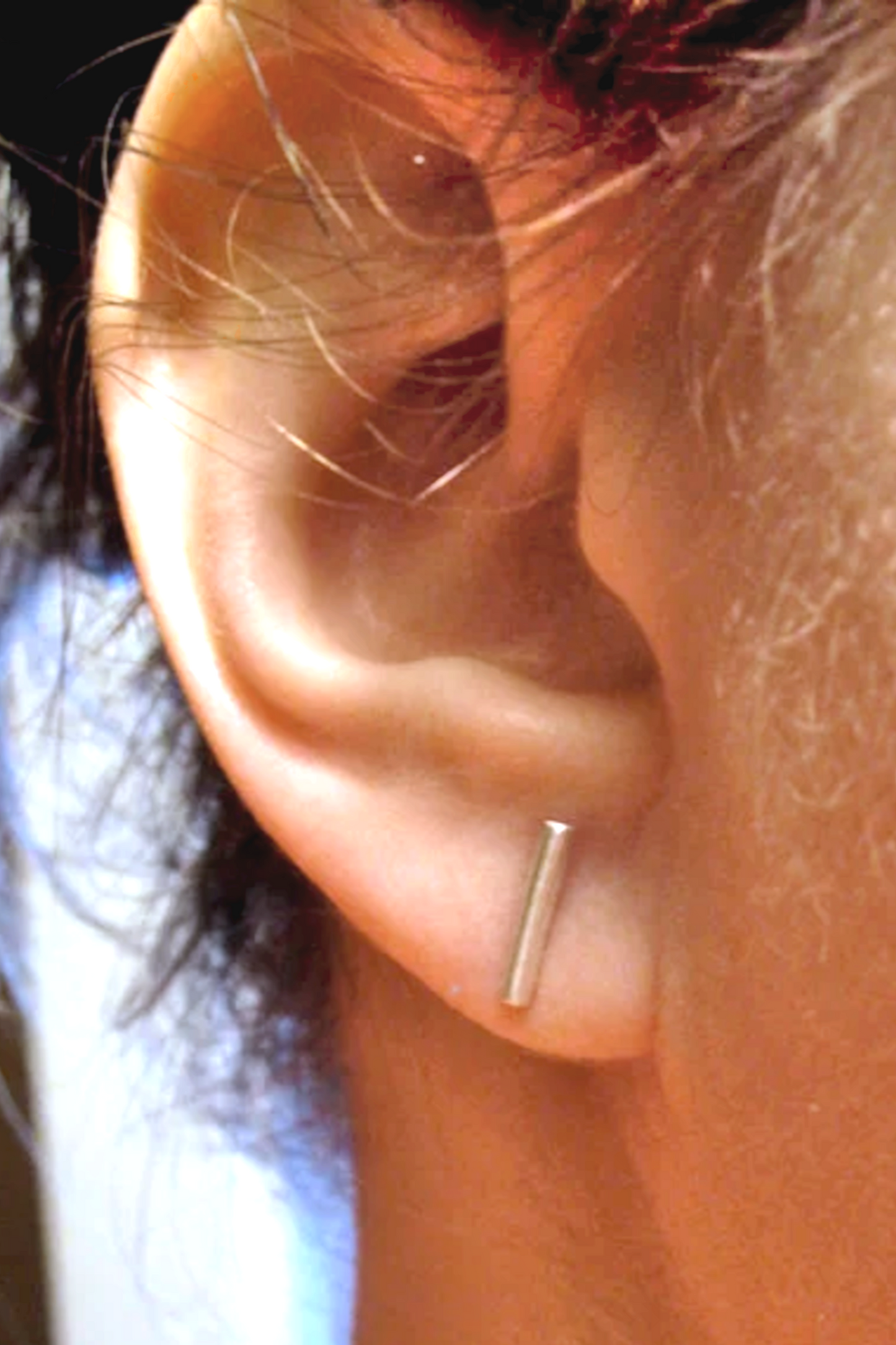 Close-up of an ear with a silver stud earring.