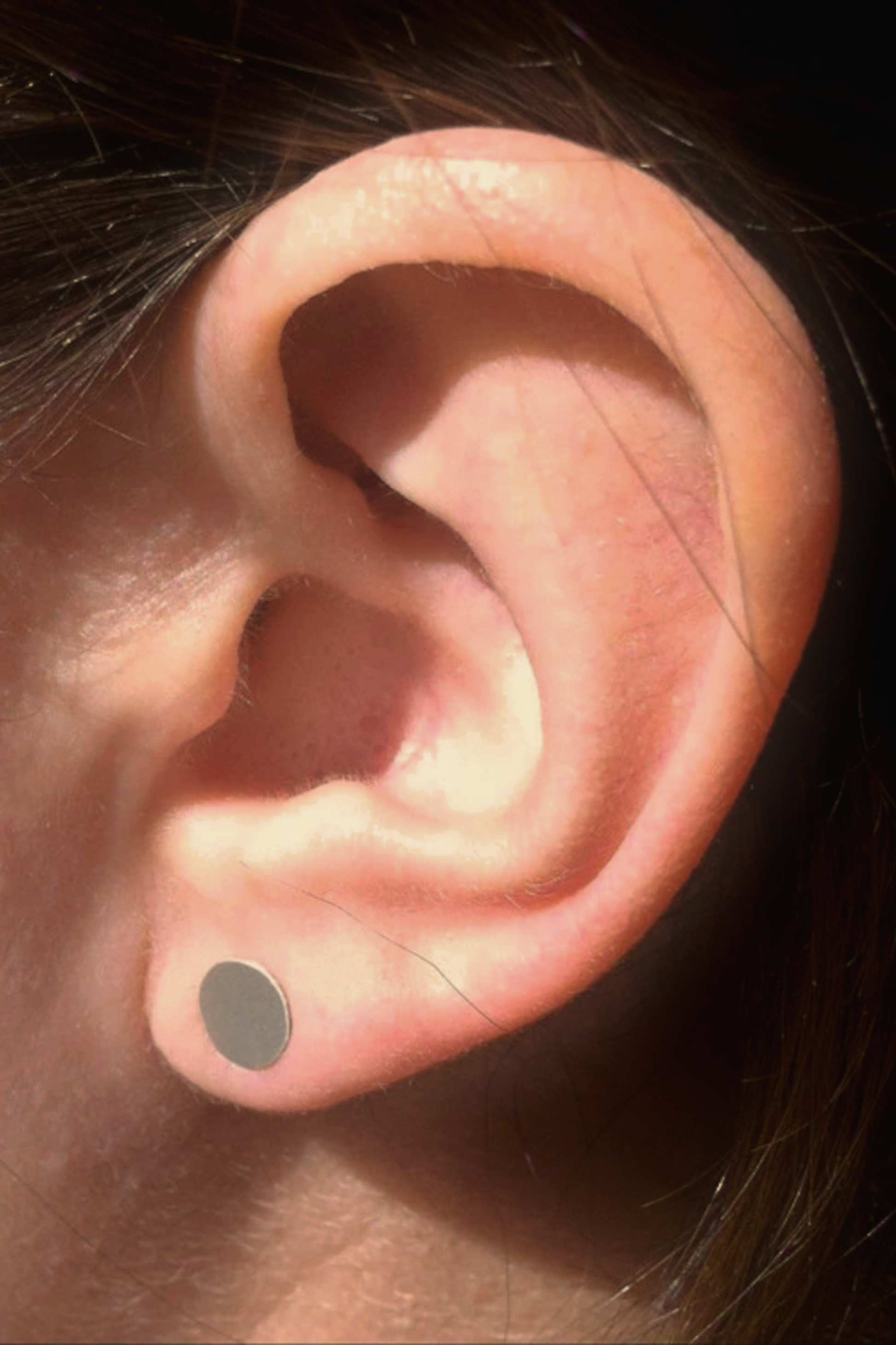Close-up of a person's ear with a small round earring.