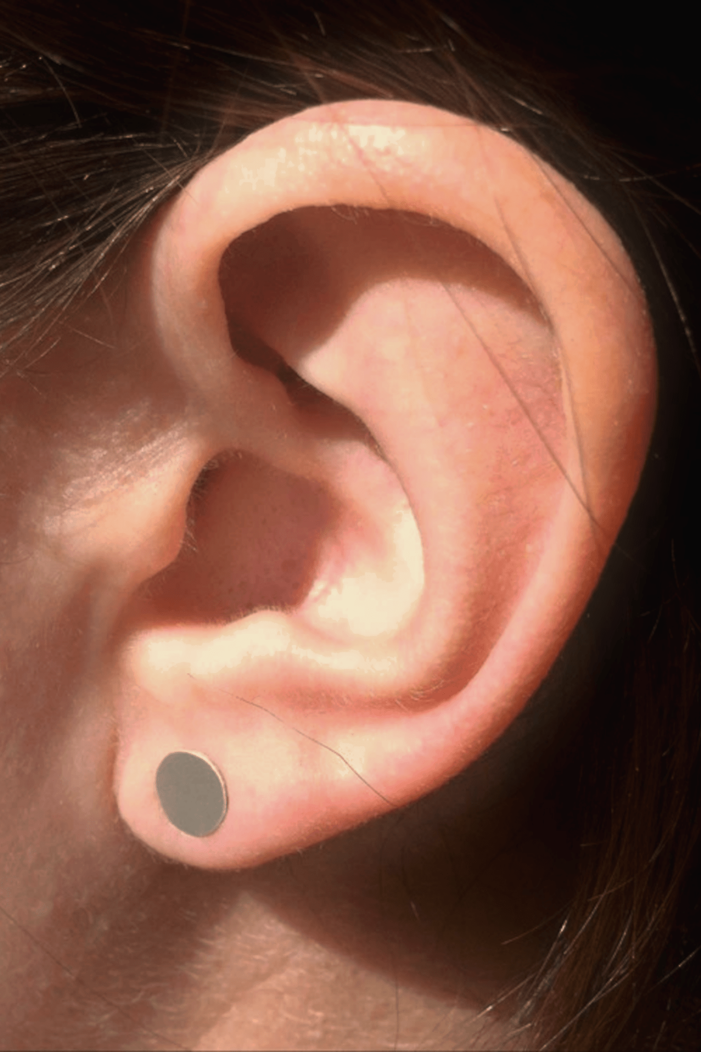 6mm matte sterling silver circle stud earrings on ear.