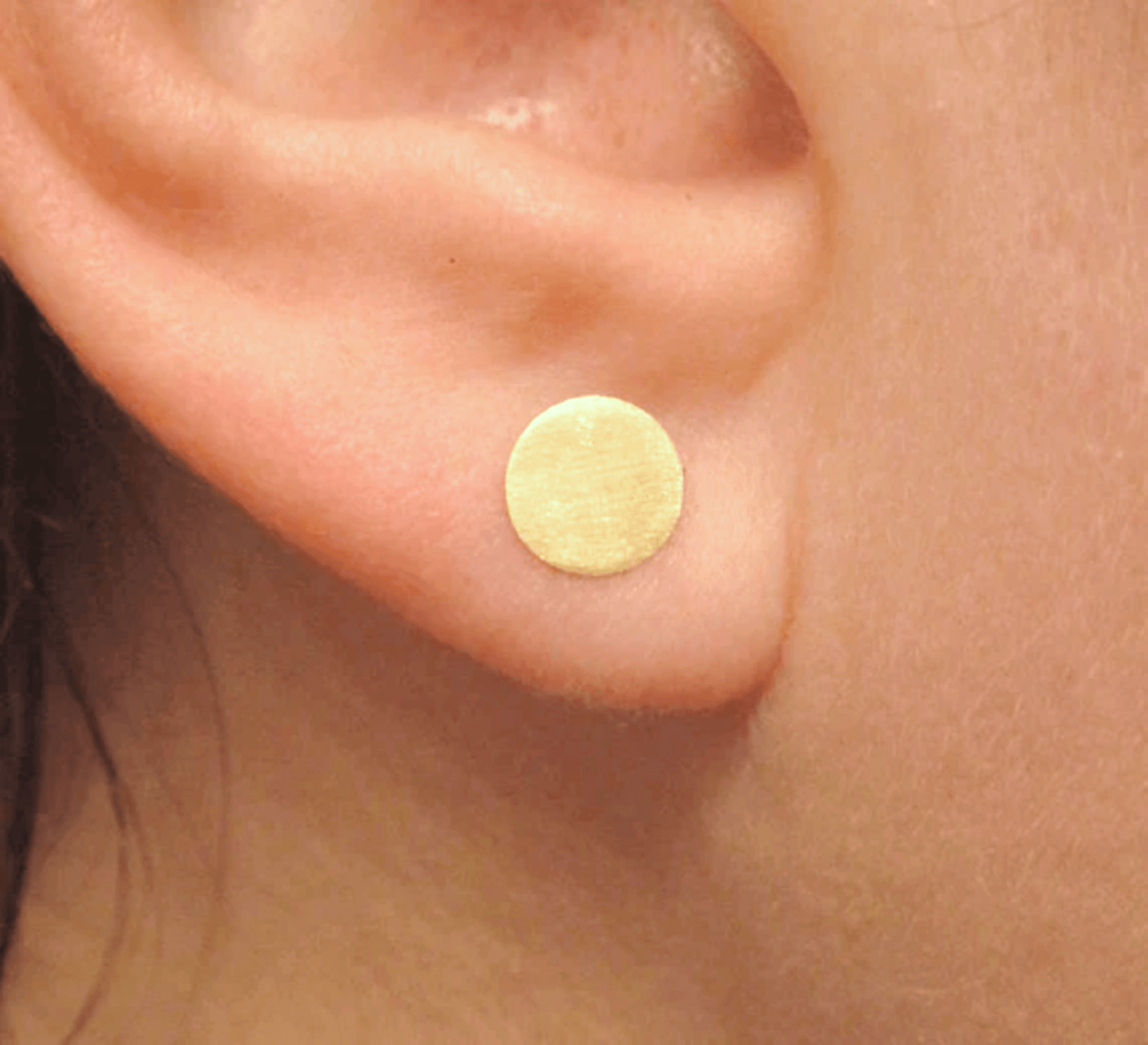 5mm brass circle stud earrings being worn, showcasing minimalist style.
