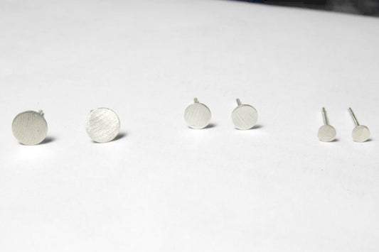 Three pairs of matte sterling silver circle studs (4mm, 5mm, 6mm) on a flat surface