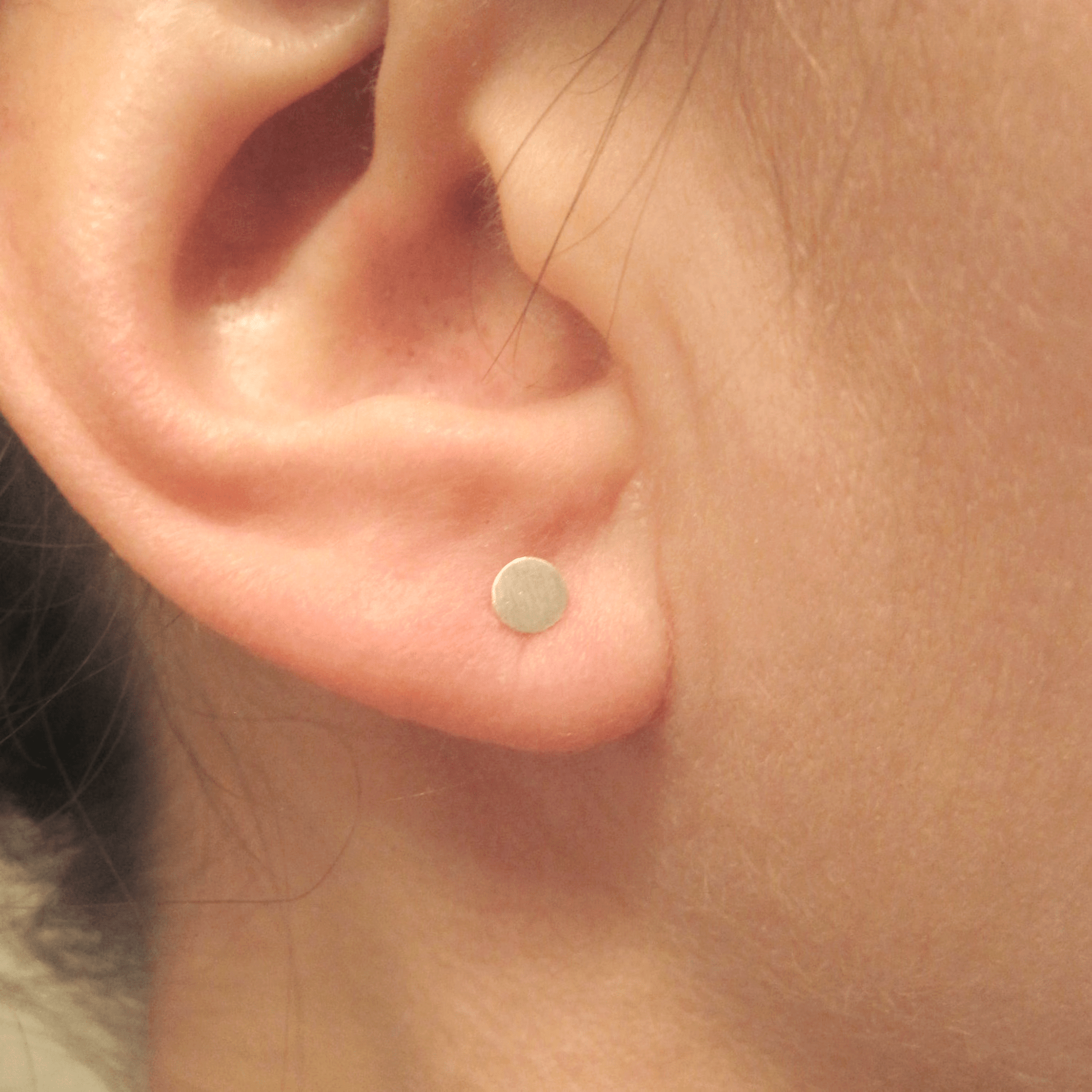 4mm sterling silver circle stud earrings on ear.