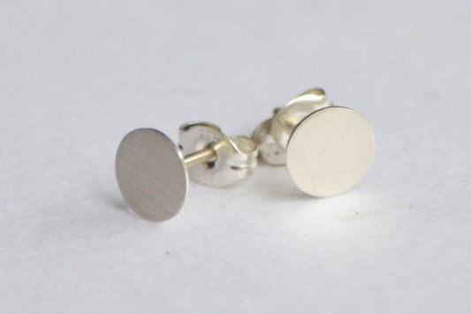 Pair of silver round earrings on a light gray background