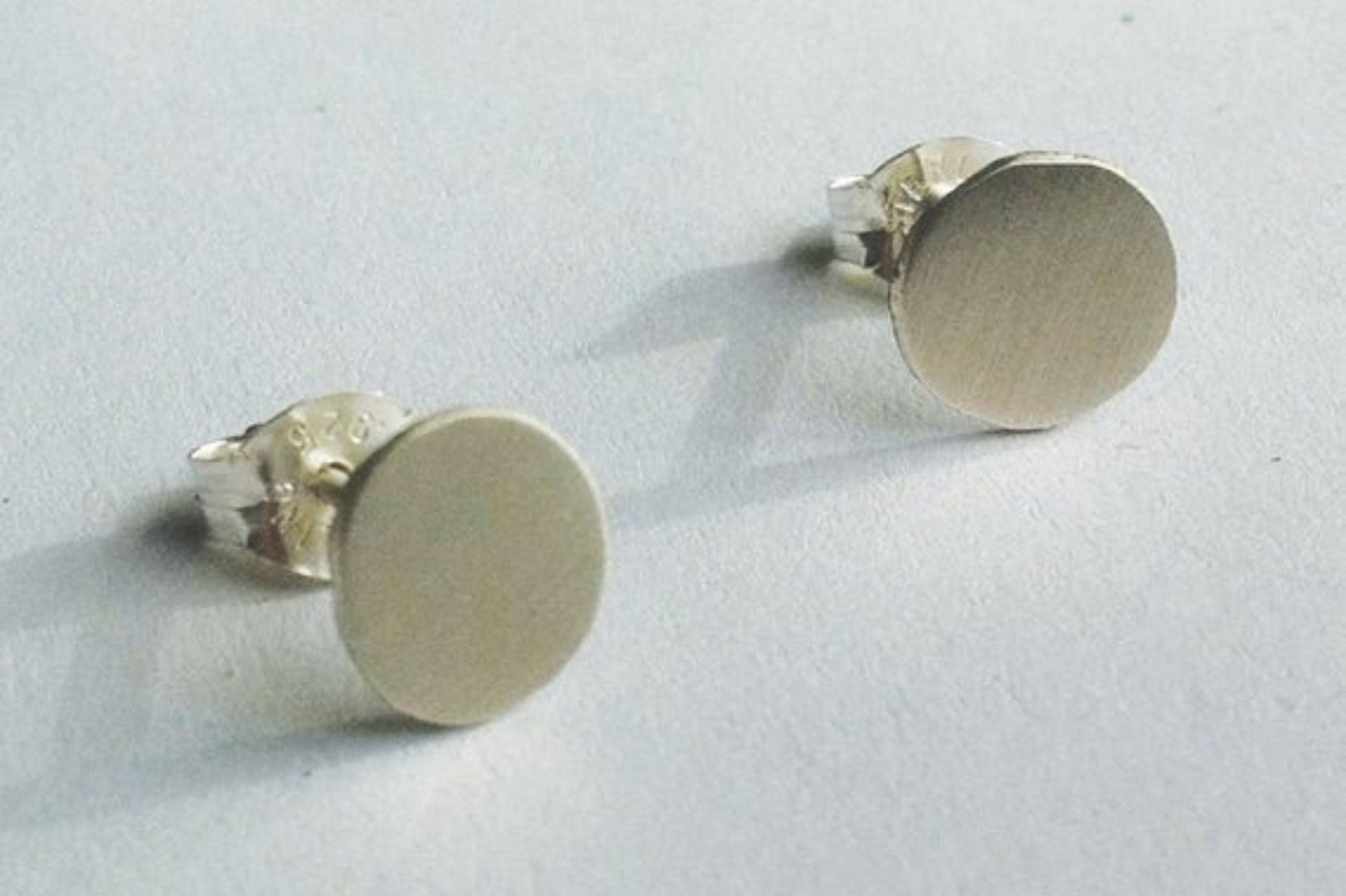 Pair of silver round stud earrings on a light gray background