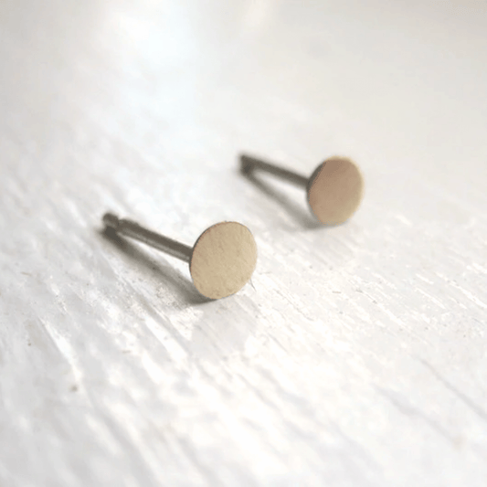 Close-up of brass circle studs with earring backs visible