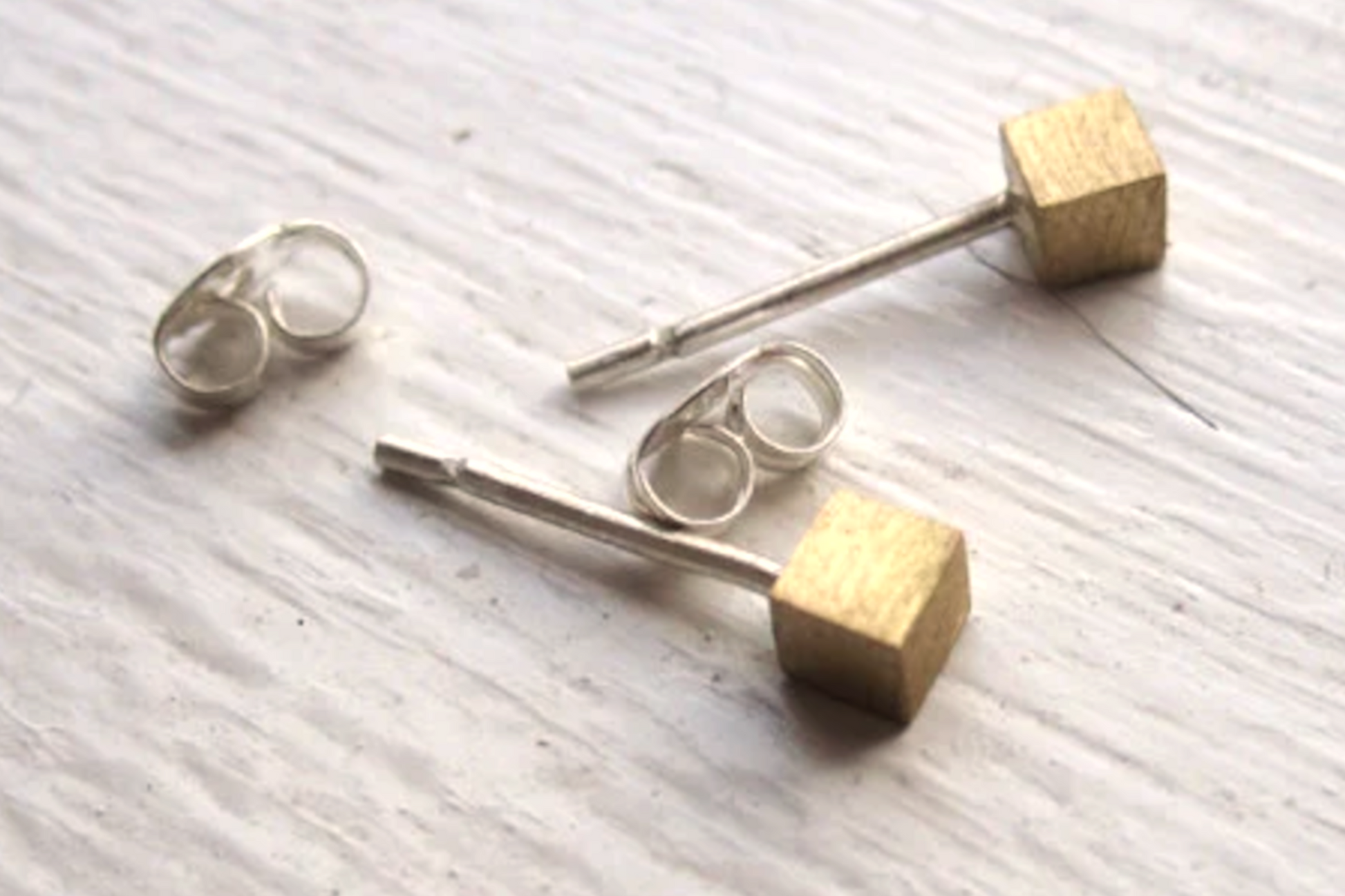Gold and silver earrings on a light wooden surface