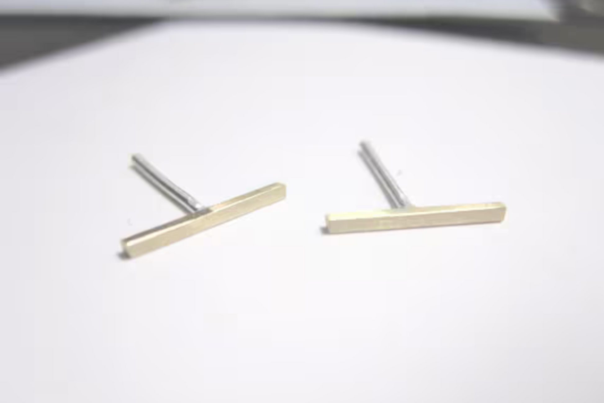 Pair of gold and silver bar-shaped earrings on a white background