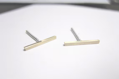 Pair of gold and silver bar-shaped earrings on a white background