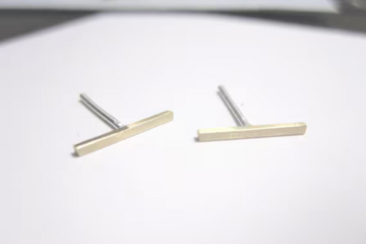 Pair of gold and silver bar-shaped earrings on a white background