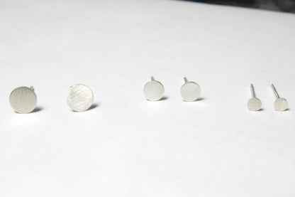Three pairs of matte sterling silver circle studs (4mm, 5mm, 6mm) on a flat surface