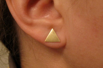 Gold triangle earring worn on an ear