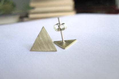 Brass triangle-shaped earrings on a white surface